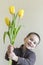 Boy hiding flower on his hands. Light background. European appearance.