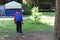 Boy on his back with his head down looking at the ground with a blue backpack. Tired boy walks to a tent with a walkie talkie in