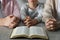 Boy and his godparents praying together at grey table, closeup