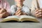 Boy and his godparents praying together at grey table, closeup