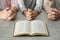 Boy and his godparents praying together at grey table, closeup