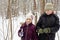 Boy and his sister stand in winter park with ski poles