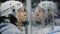 Boy in hockey hardhat watches game near transparent shield