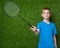 Boy holding badminton racket over green grass