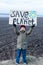 A boy holding a cardboard sign save the planet on the background of arable land. Farmland preservation concept