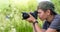 Boy holding digital camera and shooting butterfly on the wild flower