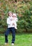 Boy holding his baby sister standing under a red tree