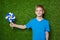 Boy holding pinwheel over green grass