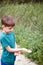 Boy Holding Small Frog At Outdoor Activity Camp Catch To Study Pond Life