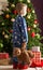 Boy Holding Teddy Bear In Front Of Christmas Tree