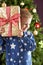 Boy Holding Wrapped Present In Front Of Tree