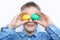 The boy holds colorful eggs. Green and yellow egg in the hands of the boy. Cheerful boy holds eggs near the eyes. White background