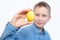 The boy holds colorful eggs. Yellow egg in the boy`s hands. Cheerful boy holds eggs near the eyes. White background