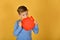 The boy holds in his hand a blank red plate in the form of an apple, a place for advertising or inscription