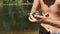 Boy Holds Little Turtle in Arms on Background of River Bank