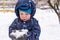 The boy holds snow in hands