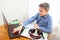 A boy at home in front of a computer does his homework. Distance learning in quarantine. Textbooks, headphones are on the table