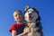 Boy hugged with love Siberian husky dog on blue background.  on blue. Family lifestyle.