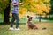 Boy hugging dog and plyaing with in the fall, city park