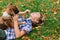 Boy hugging dog and plyaing with in the fall, city park