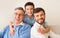 Boy Hugging Father And Grandfather Smiling At Camera At Home
