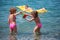 Boy on inflatable mattress in sea and girls nearby