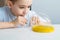 A boy inflates a ball from a slime. Close-up child in a white T-shirt at a white table plays a slime