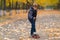 Boy in jacket standing on skateboard with one foot, going to move forward. Full length front portrait in the park covered with