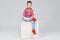 Boy in jeans and sneakers is sitting on a cube on an isolated white background.
