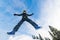 Boy jumping from snow hill, trees around, cloudy sky background, Sweden