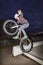 Boy jumps with his dirtbike in the skate park over a ramp