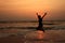 A boy jumps in the waves during sunset