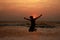 A boy jumps in the waves during sunset