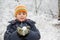 Boy keeps in hands snowball in wood in winter