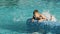 Boy keeps on pool edge and kicking with their legs splashing the water