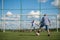 Boy kicking a penalty at goal playing with his father on a green grass.