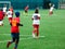 Boy is kicking soccer ball. Boy is running after the ball on green grass. footballer in white and red shirt. boys dribbling.