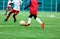 Boy is kicking soccer ball. Boy is running after the ball on green grass. footballer in white and red shirt. boys dribbling.