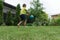 Boy is kicking up and catching back football ball on green grass of backyard.