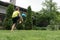 boy is kicking up football ball on green grass of backyard.