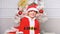 Boy kid dressed as cute elf magical creature white artificial ears and red hat near christmas tree. Christmas elf
