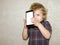 A boy kid looks into the camera of a smartphone, shows the screen with his digital photo.