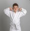 Boy in kimono holds his hands up shows his strength. Gray background