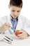 Boy in lab coat injecting blue liquid into apple