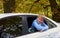 Boy leaned out of the window of a parked white car