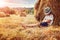 Boy leaning and sleeping against a haystack at sunset