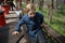 Boy leans his hands on the railing and a wooden table in a cafe in the spring in the park