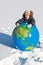 Boy leans on inflatable globe in winter