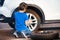 Boy learning how to change tyre using wheel brace