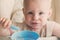 Boy learning to eat. cute messy baby eating vegetables with spoon by yourself in highchair